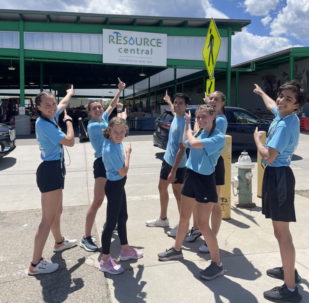 A group of jump ropers smile and point at the Resource Central logo behind them. 