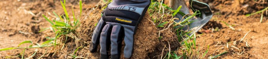 A person's hands picking up a pile of sod