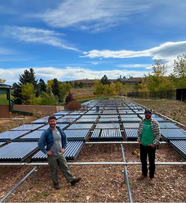 Two people stand in front of a field of solar tube panels.