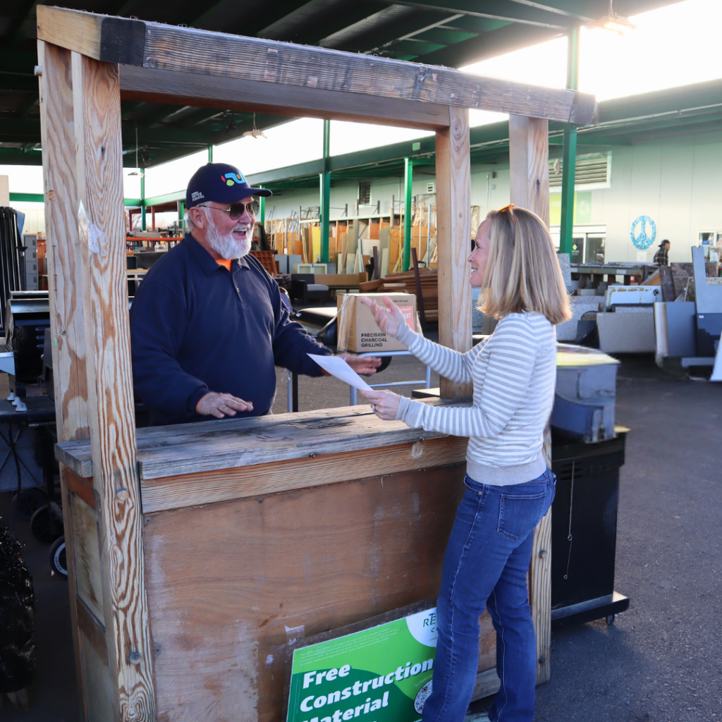 Two people smile and talk at an information booth.