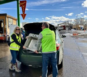 Two volunteers in bright green vests unload a sink from a car in the Resource Central donation lane.