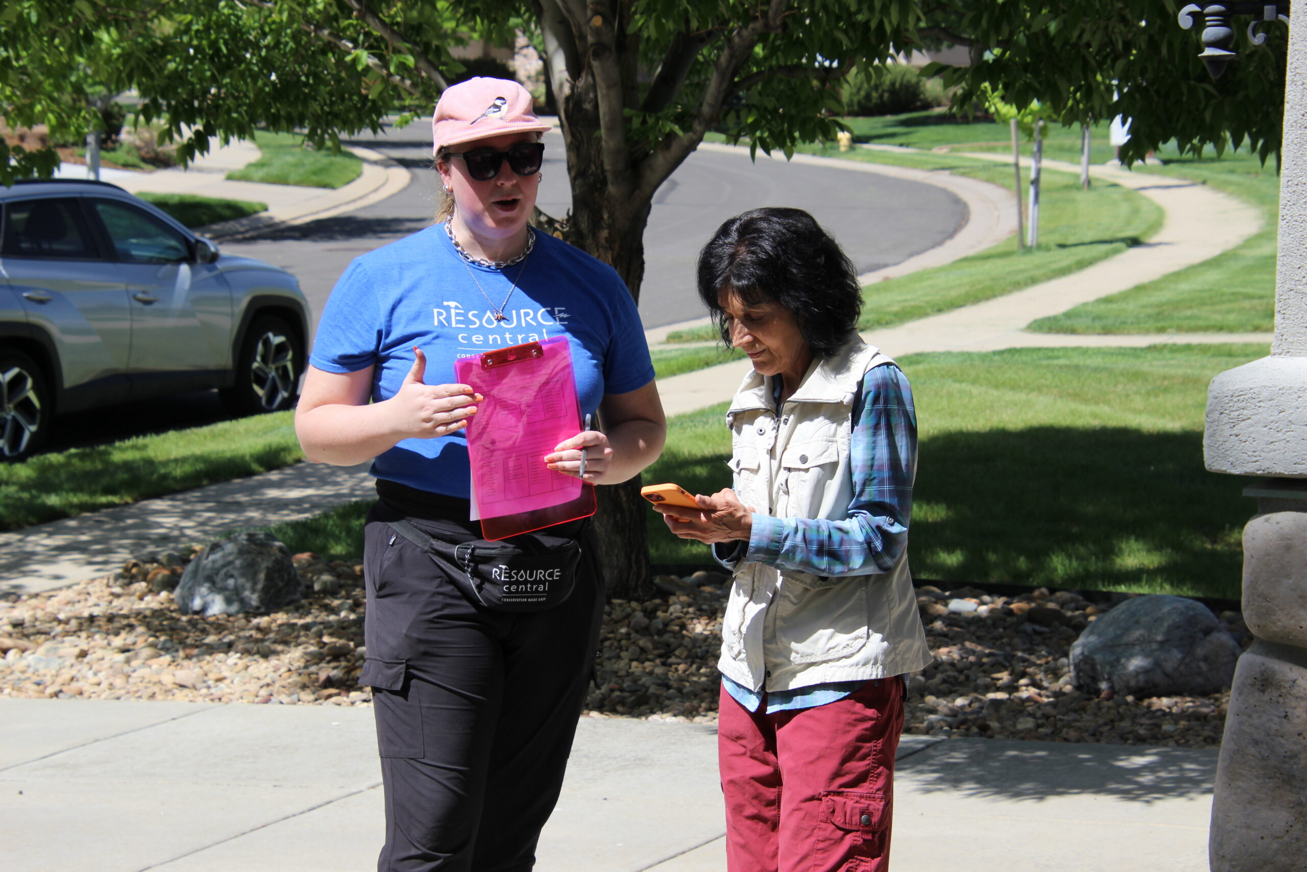 A sprinkler technician and a homeowner review information together in the front yard.
