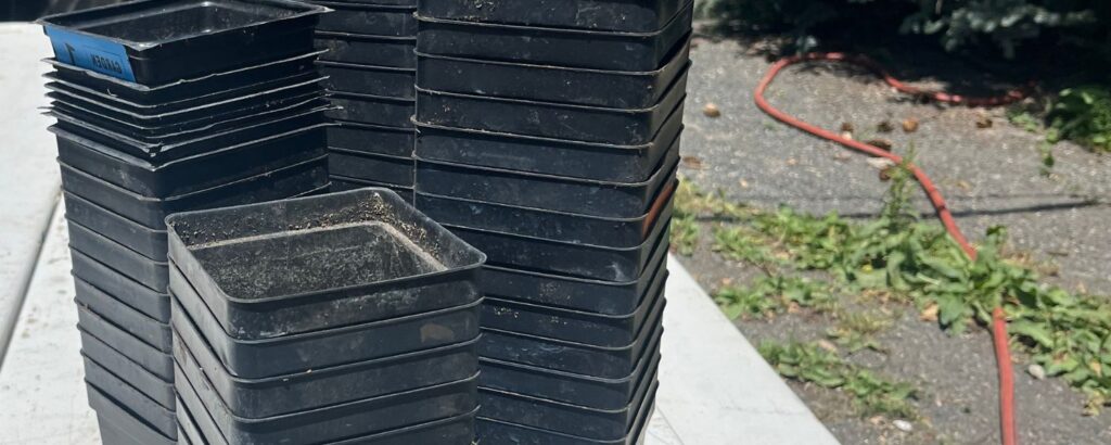 Stacks of black plastic plant pots on a table. 