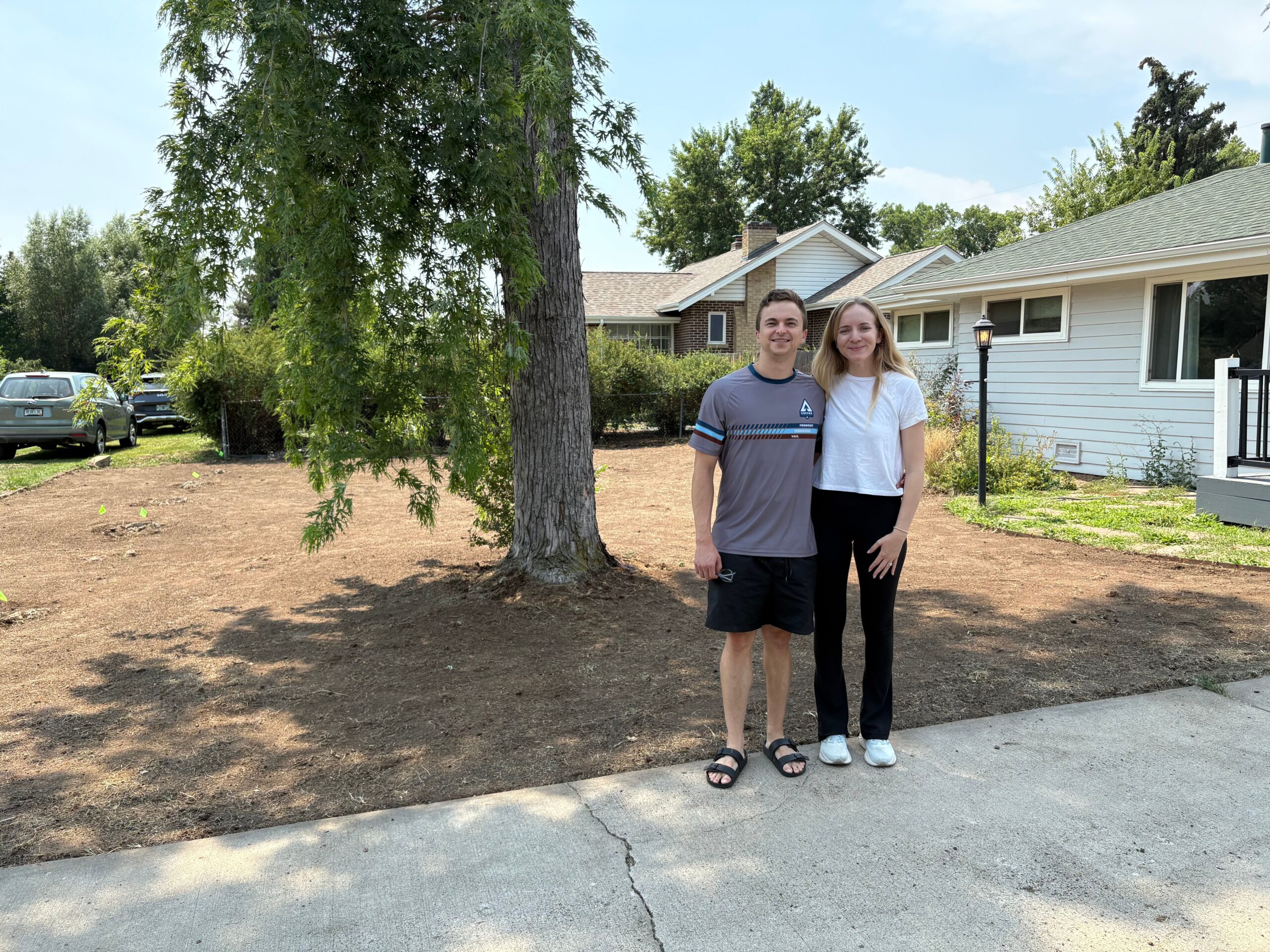 Two homeowners stand in their yard after the grass was removed.