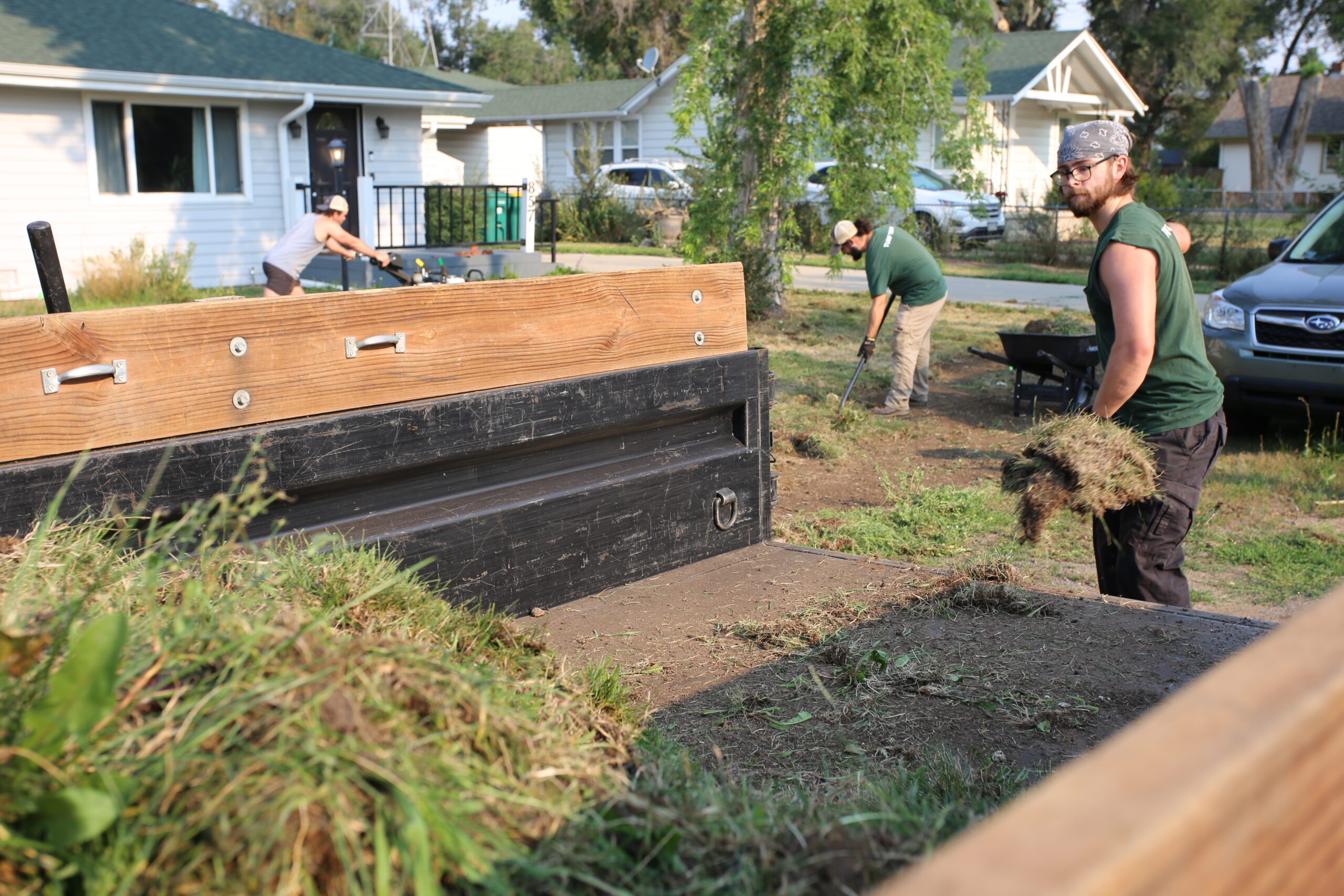 A Lawn Removal crew member loading grass into the bed of a trailer.