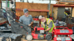 A Resource Central volunteer shows a staff member how to repair a lawn mower