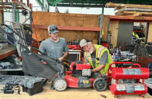 A Resource Central volunteer shows a staff member how to repair a lawn mower