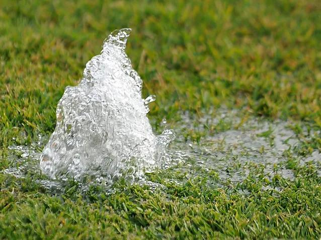 Geyser of water forming from an area of a sprinkler system that has missing a sprinkler head.