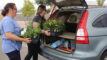 Two volunteers load up a car with plants from a Garden In A Box kit.