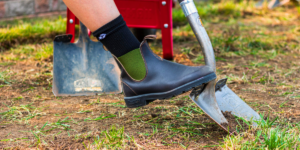 Blundstone shoe pushing shovel into the dirt to remove grass