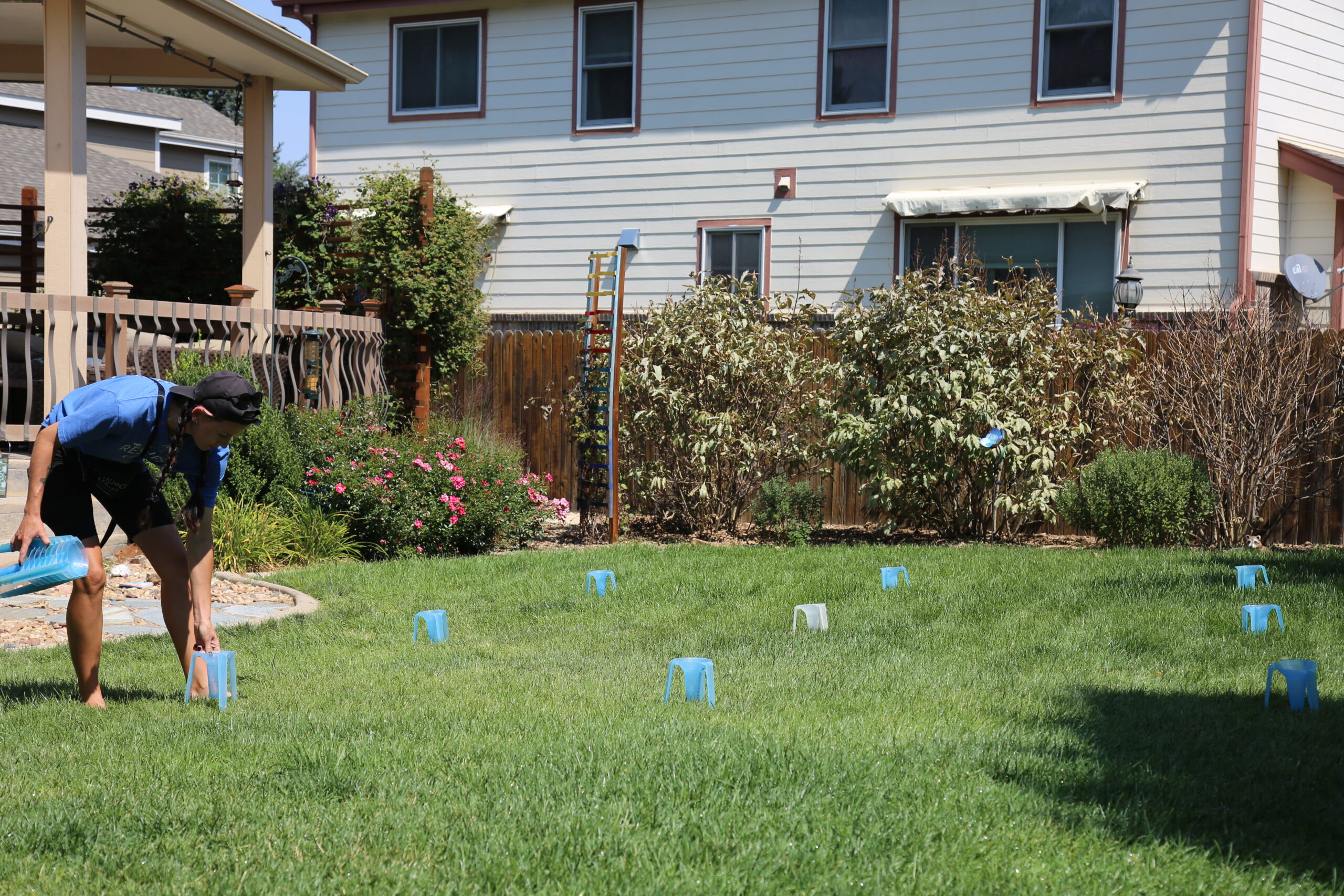 A Slow the Flow technician places rows of water collection cups in a yard