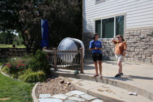 A Slow the Flow technician and a homeowner talking on a backyard patio.