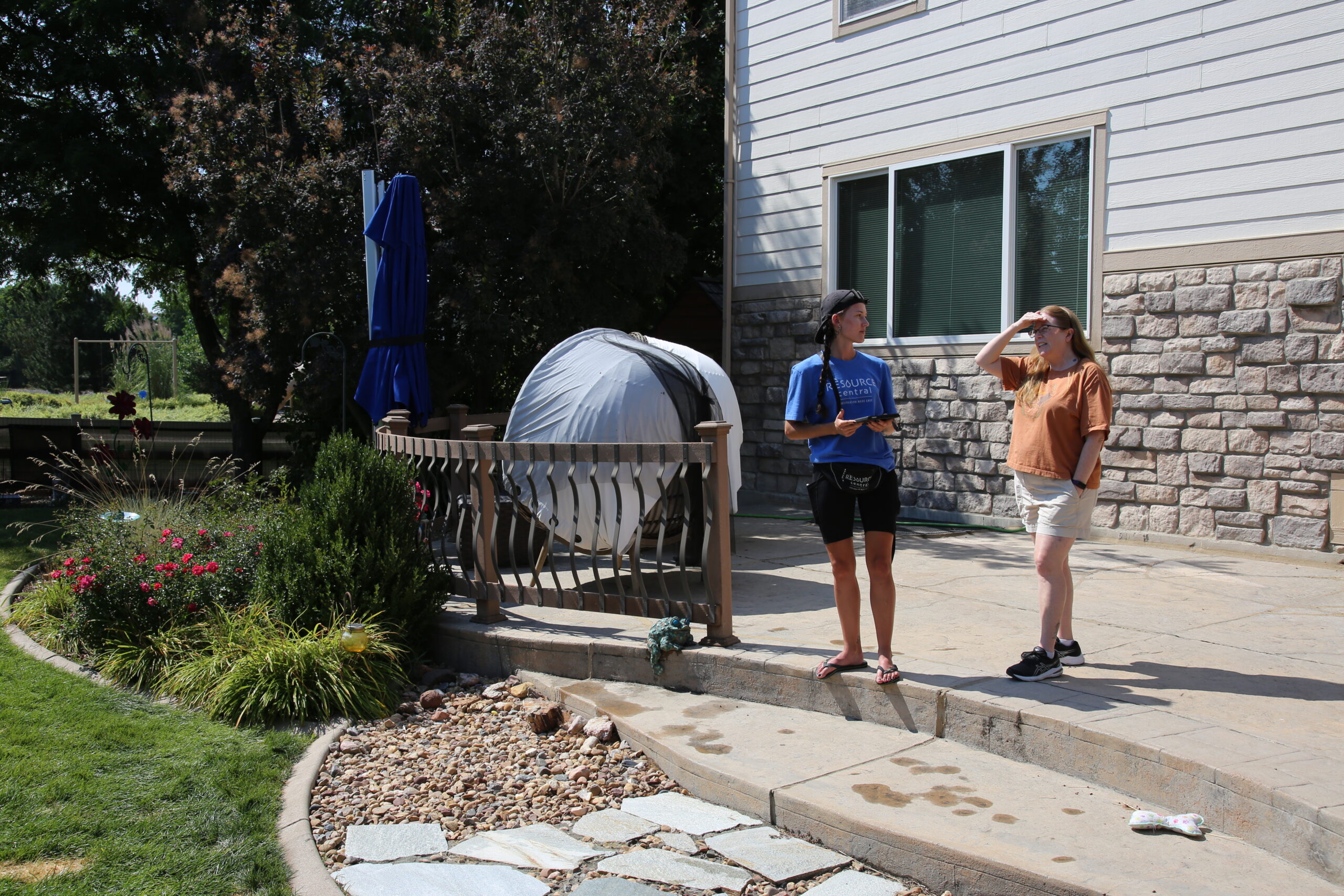 A Slow the Flow technician and a homeowner talking on a backyard patio.