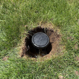 A new sprinkler head in a whole in the lawn.