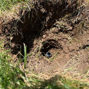small sprinkler base in a deep dirt hole - the second step to DIY sprinkler removal.