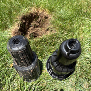 sprinkler pieces next to the hole that was dug from earlier in the sprinkler head removal process.