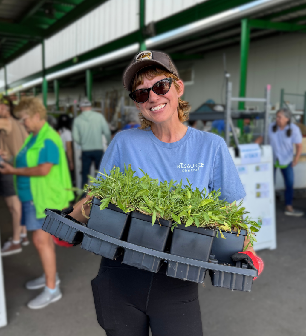 woman holding a tray of plants while smiling