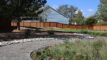 a grey gravel footpath curves through a landscape of grasses and flowering plants